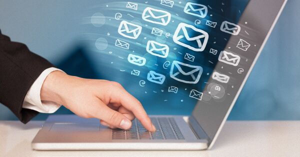 Hand typing on a laptop to send emails