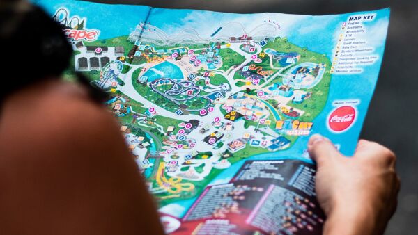 An amusement park customer manually looks at the map for directions