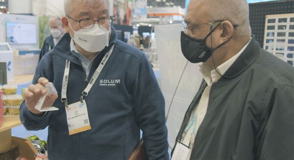 SOLUM America President JH Yoo demonstrates an ESL to a curious SOLUM booth visitor.